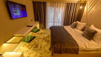 A hotel room with a bed, a desk, a TV, and a window with curtains.