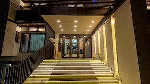 A hotel entrance with a staircase leading to the lobby, featuring a modern design with a wooden railing and illuminated steps. - Elexus (Predeal)