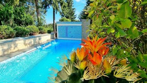 A swimming pool with a tiled deck, surrounded by lush greenery and trees. - Elexus (Predeal)