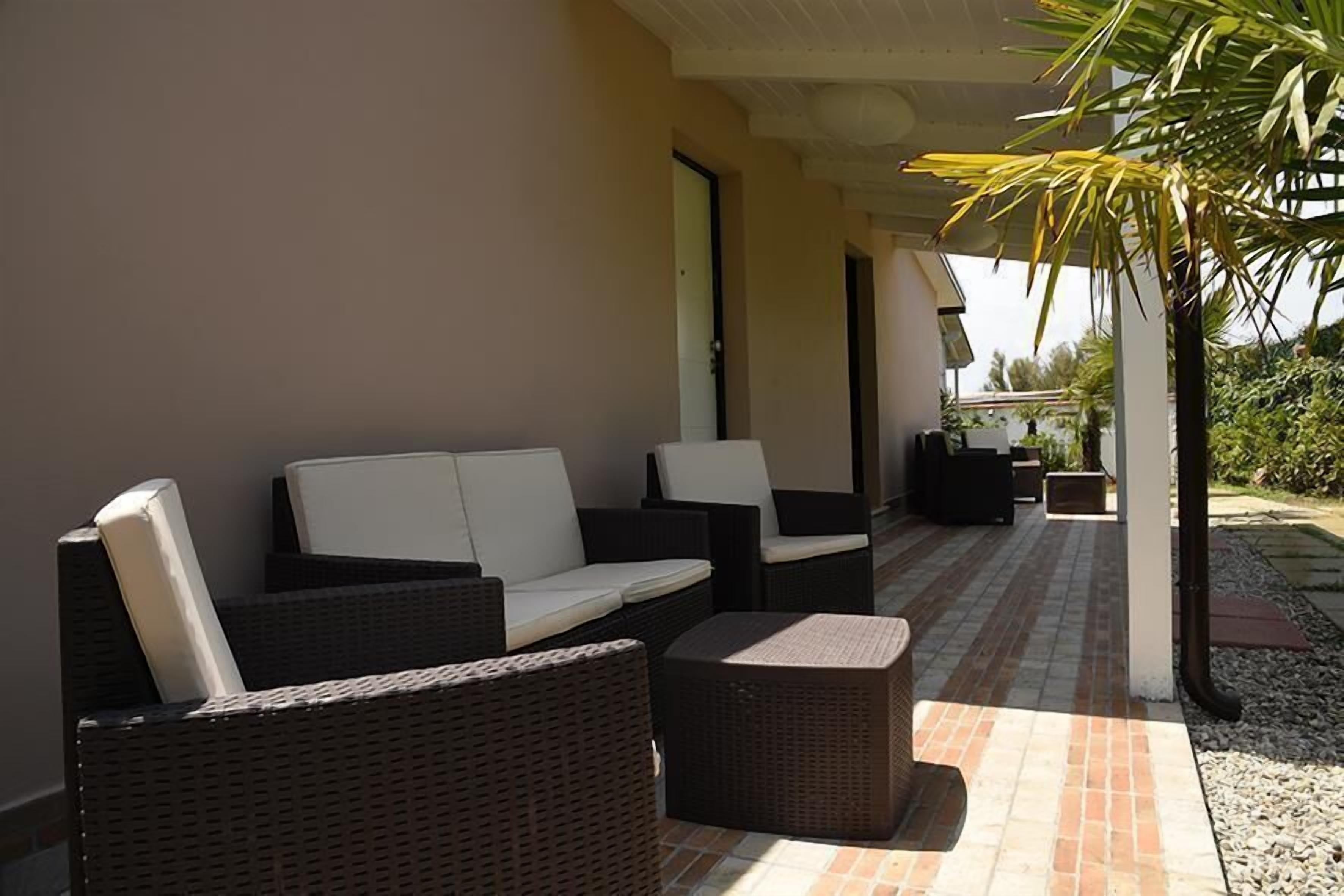 A covered outdoor seating area with wicker furniture and a tiled floor.