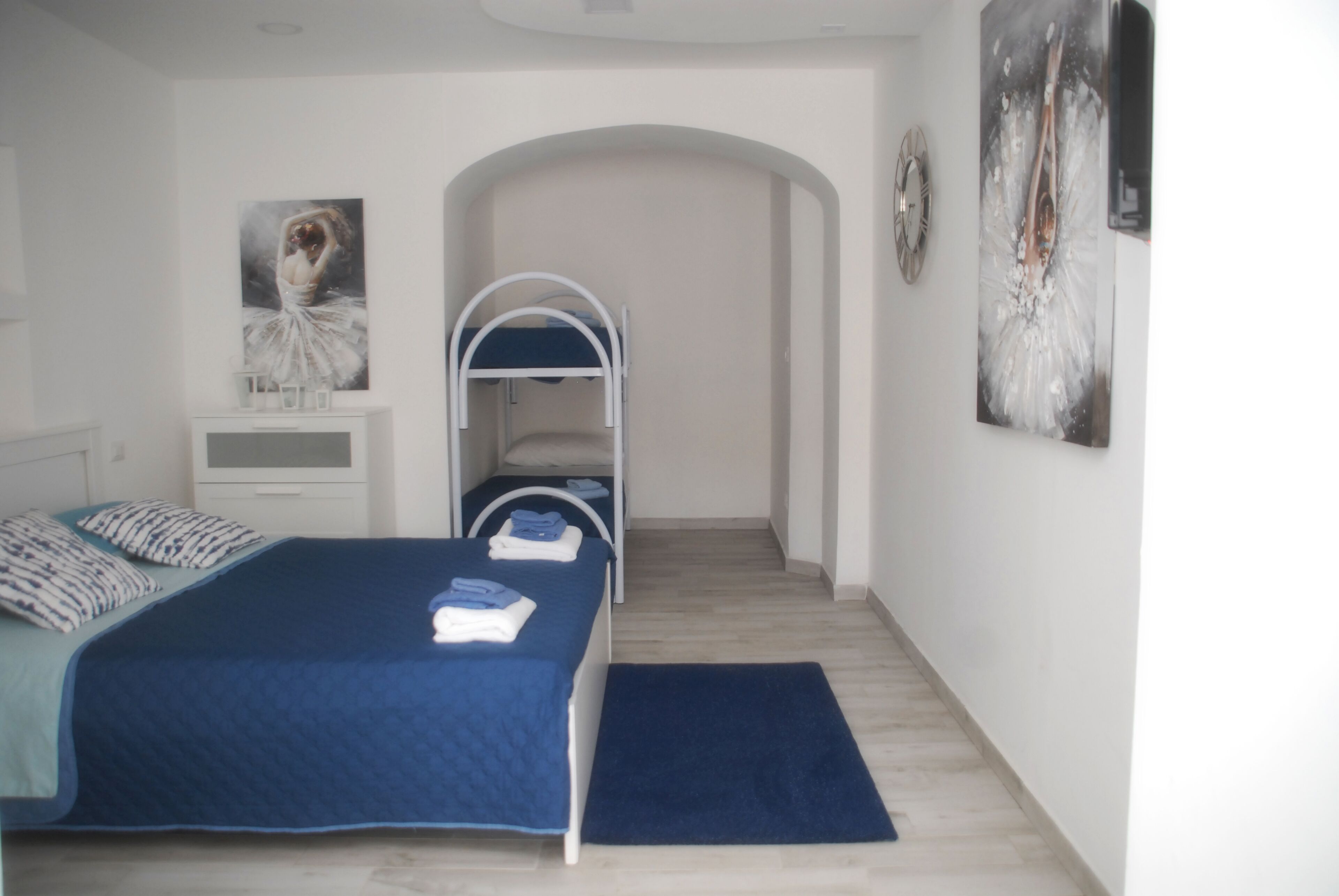 A bedroom with a bed, a nightstand, a dresser, a wardrobe, and a painting on the wall.