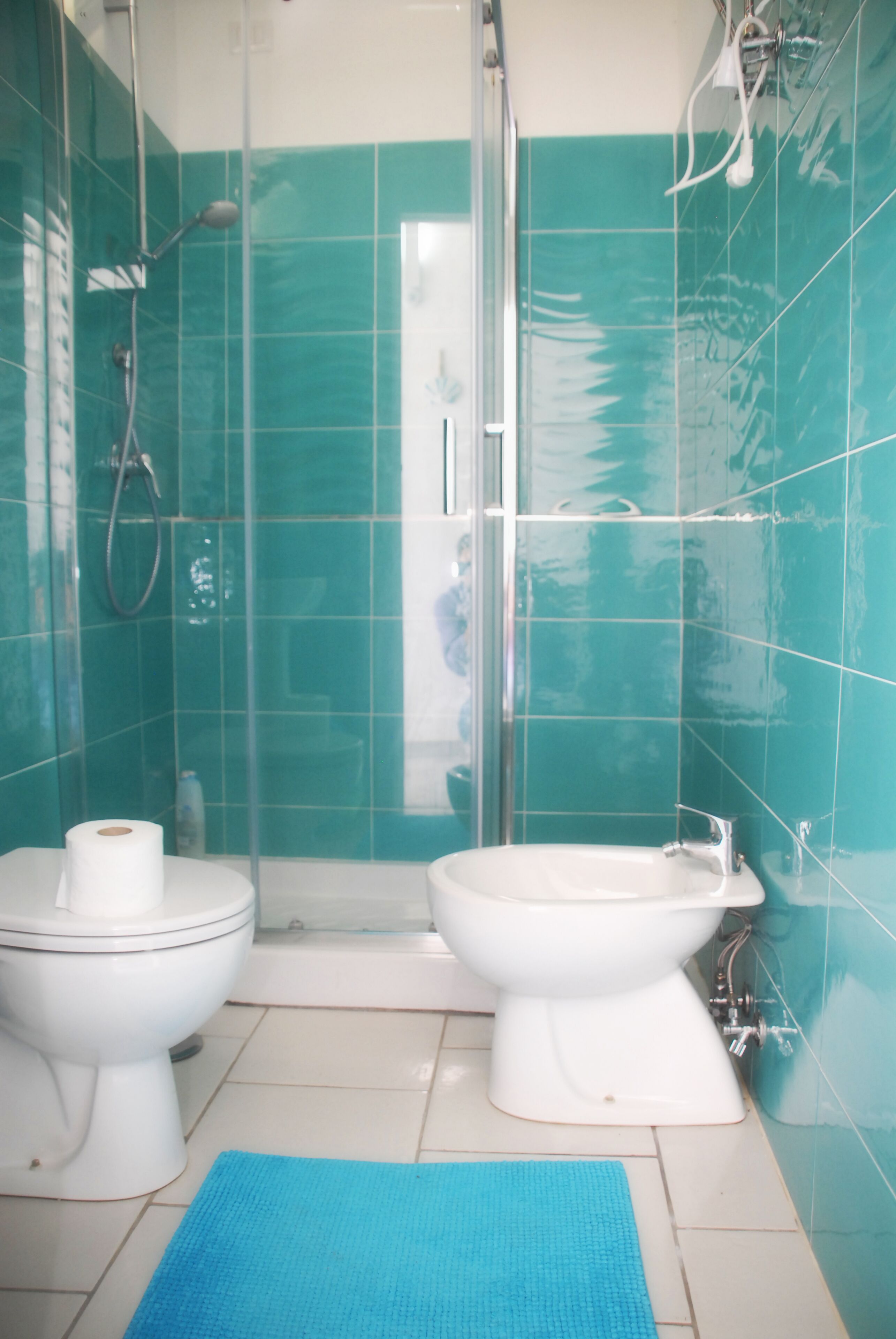 A bathroom with two toilets, a shower, and a sink.