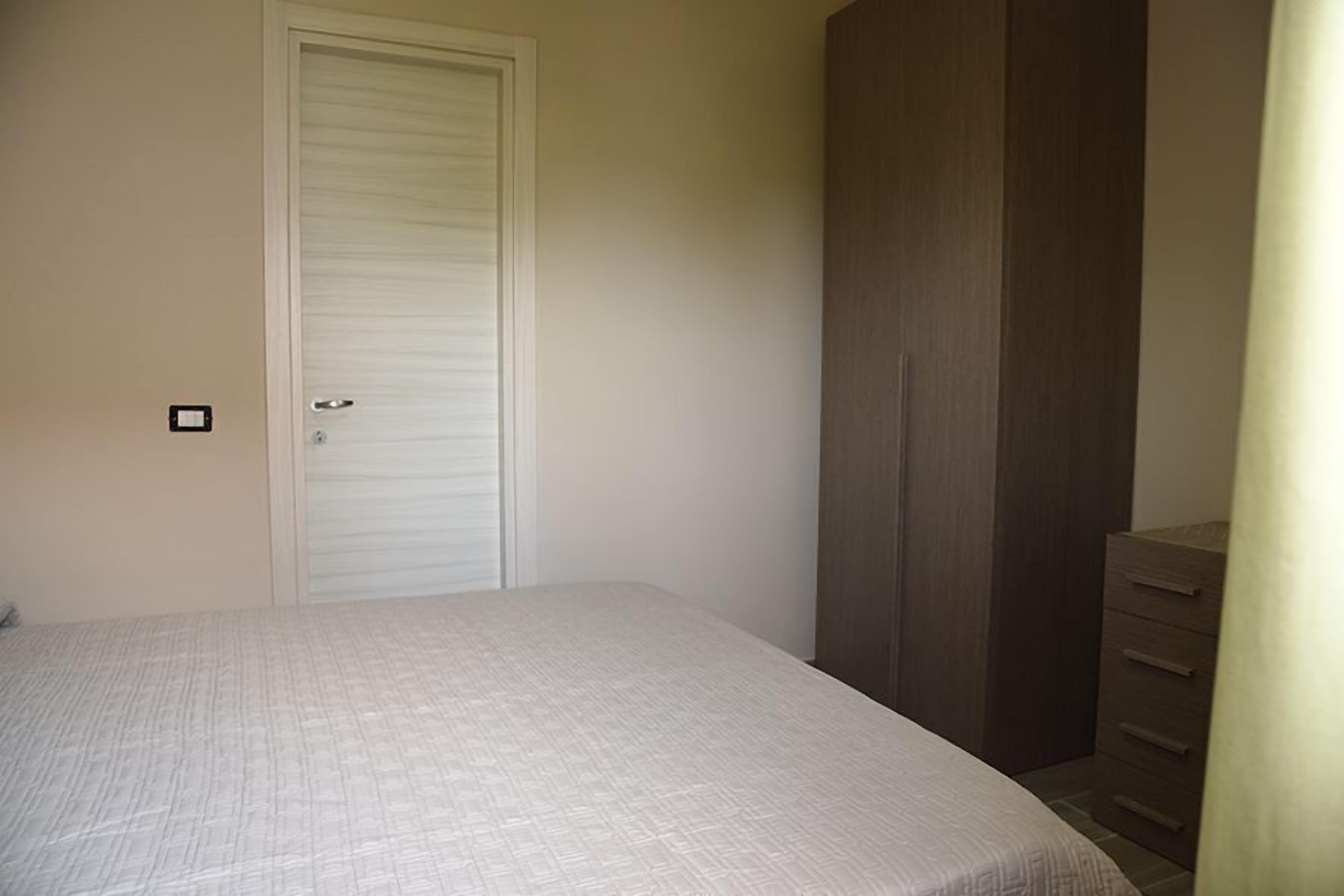 A bedroom with a bed, a wardrobe, and a dresser.