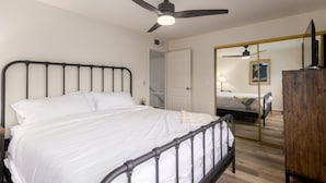 A bedroom with a bed, a ceiling fan, a wardrobe, and a mirror reflecting another bed. - Walk to Fashion Square Mall | Cozy Condo (Scottsdale)