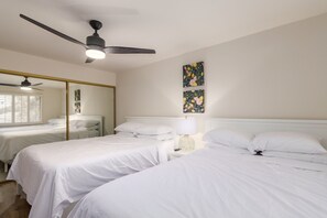 A hotel room with two single beds, a ceiling fan, a large mirror, and two floral wall art pieces. - Walk to Fashion Square Mall | Cozy Condo (Scottsdale)