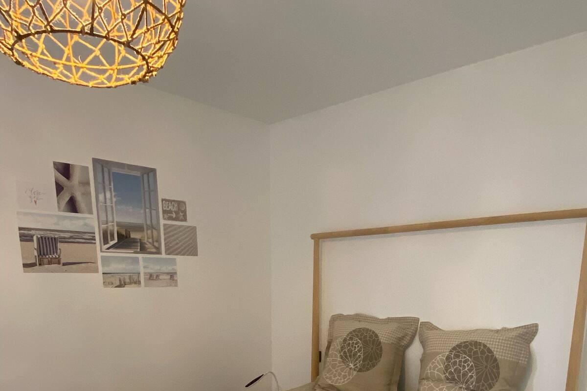 Ein Schlafzimmer mit einem Bettgestell aus Holz, einer gesteppten Bettdecke und einer Deckenleuchte.
