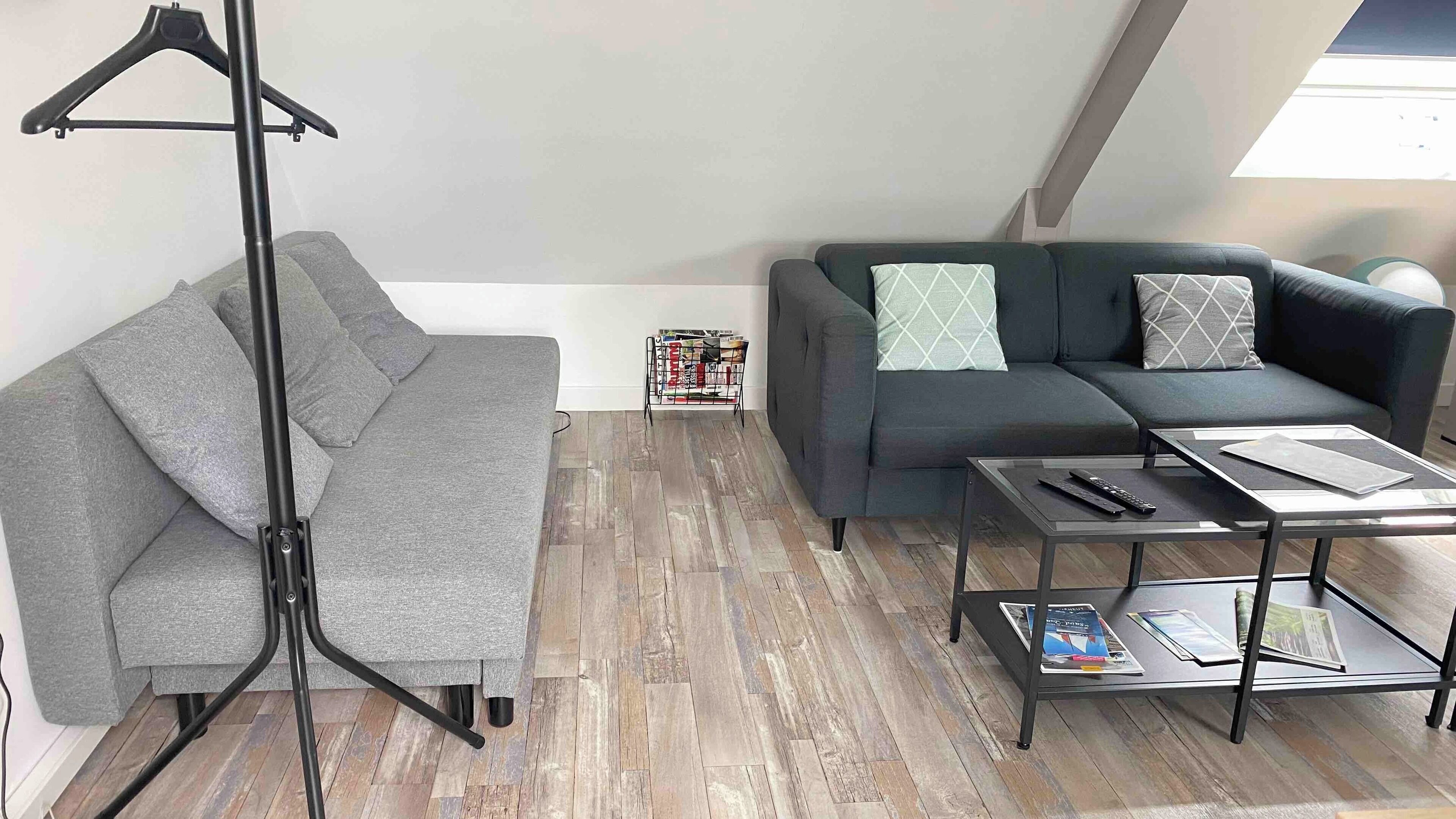 Uma sala de estar moderna com um sofá cinzento, uma mesa de centro preta e um abajur.
