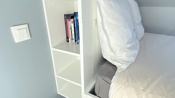 A bedroom with a white bed, a white wardrobe, and a shelf with books. - Appartements Résidence des 3 îles - Binic-Etables sur mer (Binic-Etables-sur-Mer)