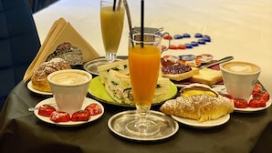 Desayuno preparado sobre una cama de hotel con un fondo de papel tapiz floral.