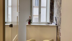 Una cocina moderna con ventana, dos taburetes de bar y una pequeña encimera con una planta.
