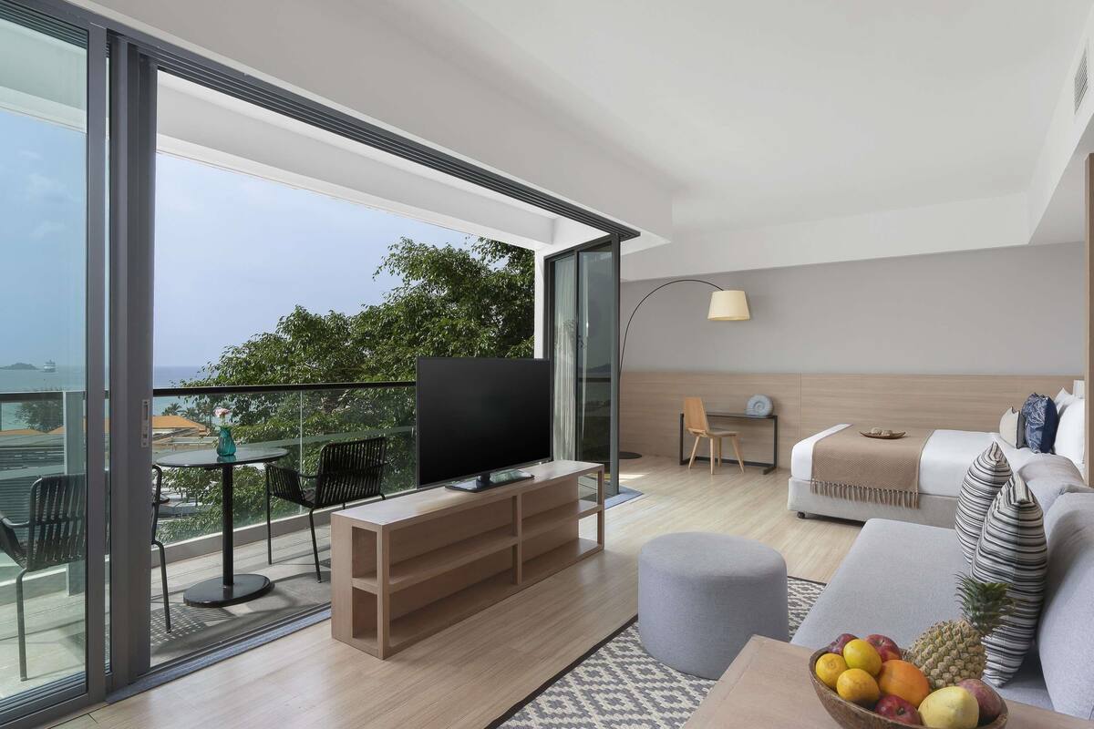 A modern living room with a TV, sofa, and a fruit bowl.