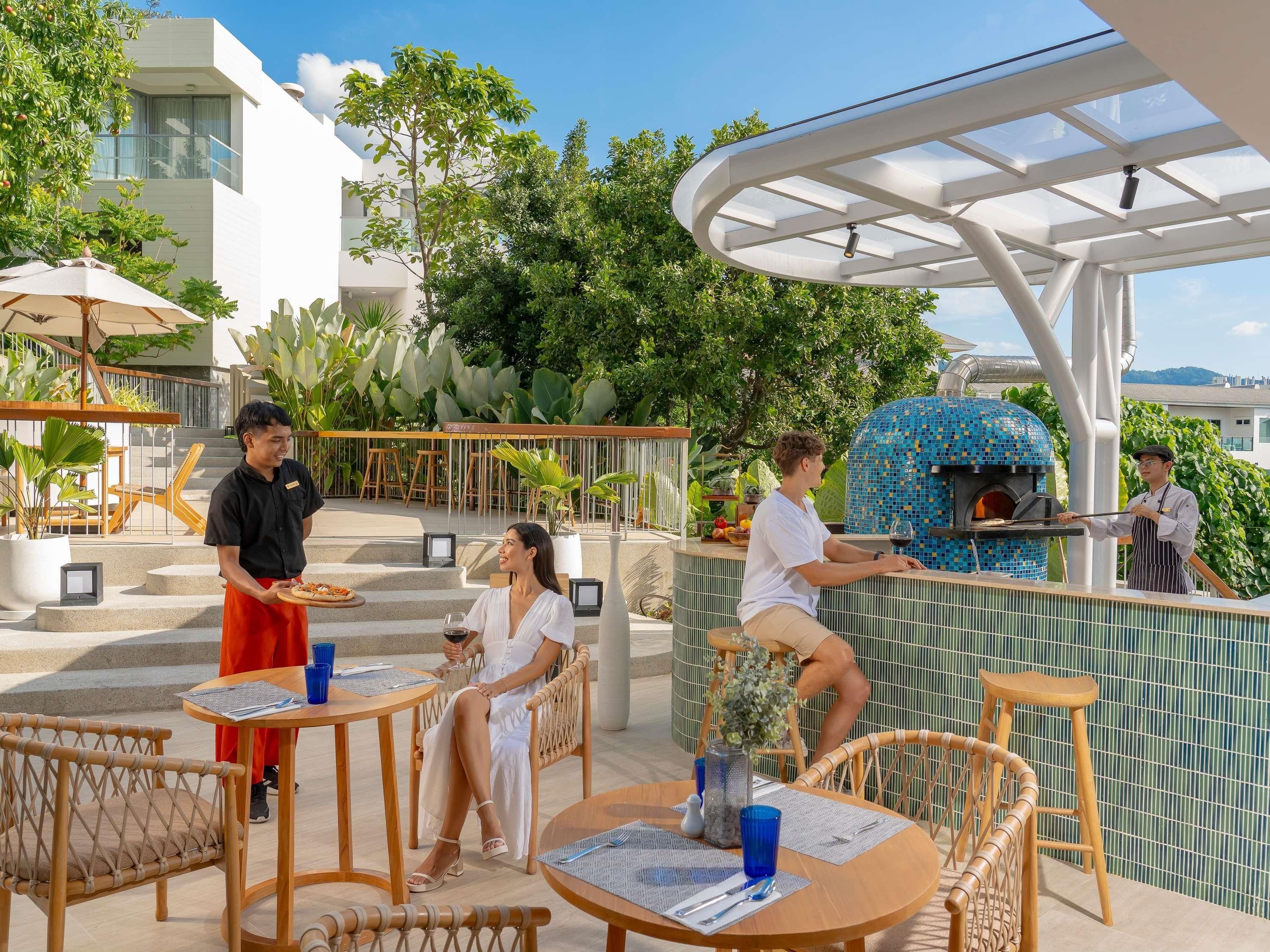 Un espacio de comedor al aire libre con horno de pizza, mesas y sillas.