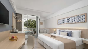 A modern hotel room with a large bed, a desk, and a balcony with a pool view.