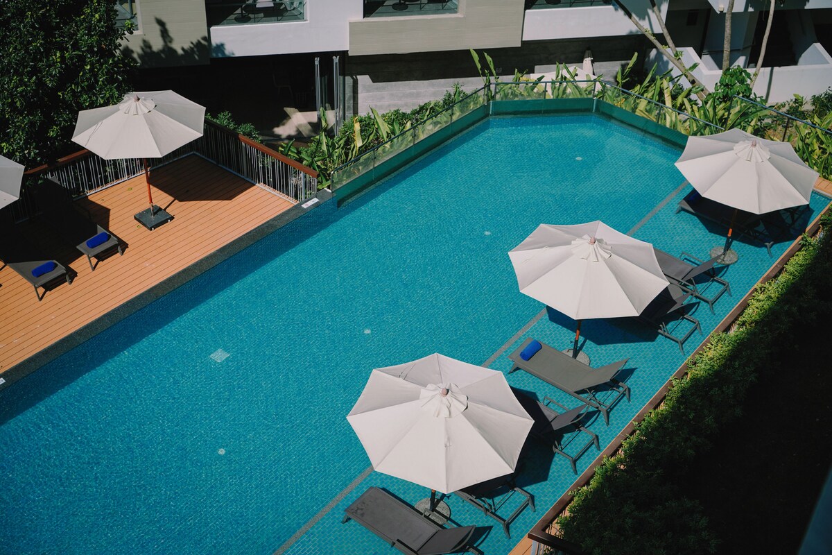 A rooftop swimming pool with lounge chairs and umbrellas.