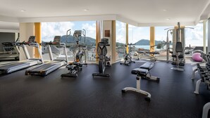 A modern gym with various exercise equipment, large windows offering scenic views. - Andaman Beach Hotel Phuket - Handwritten Collection by Accor (Patong)