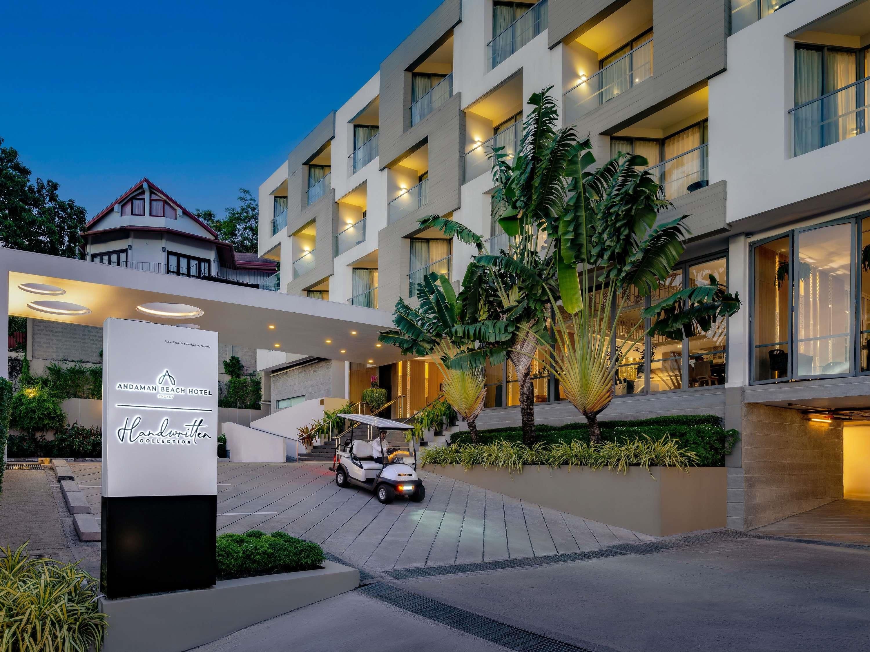 Un hotel moderno con un patio central, un letrero que dice Andaman Beach Hotel y un carrito de golf.