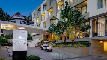 Um hotel moderno com um pátio central, uma placa com o nome Andaman Beach Hotel e um carrinho de golfe.