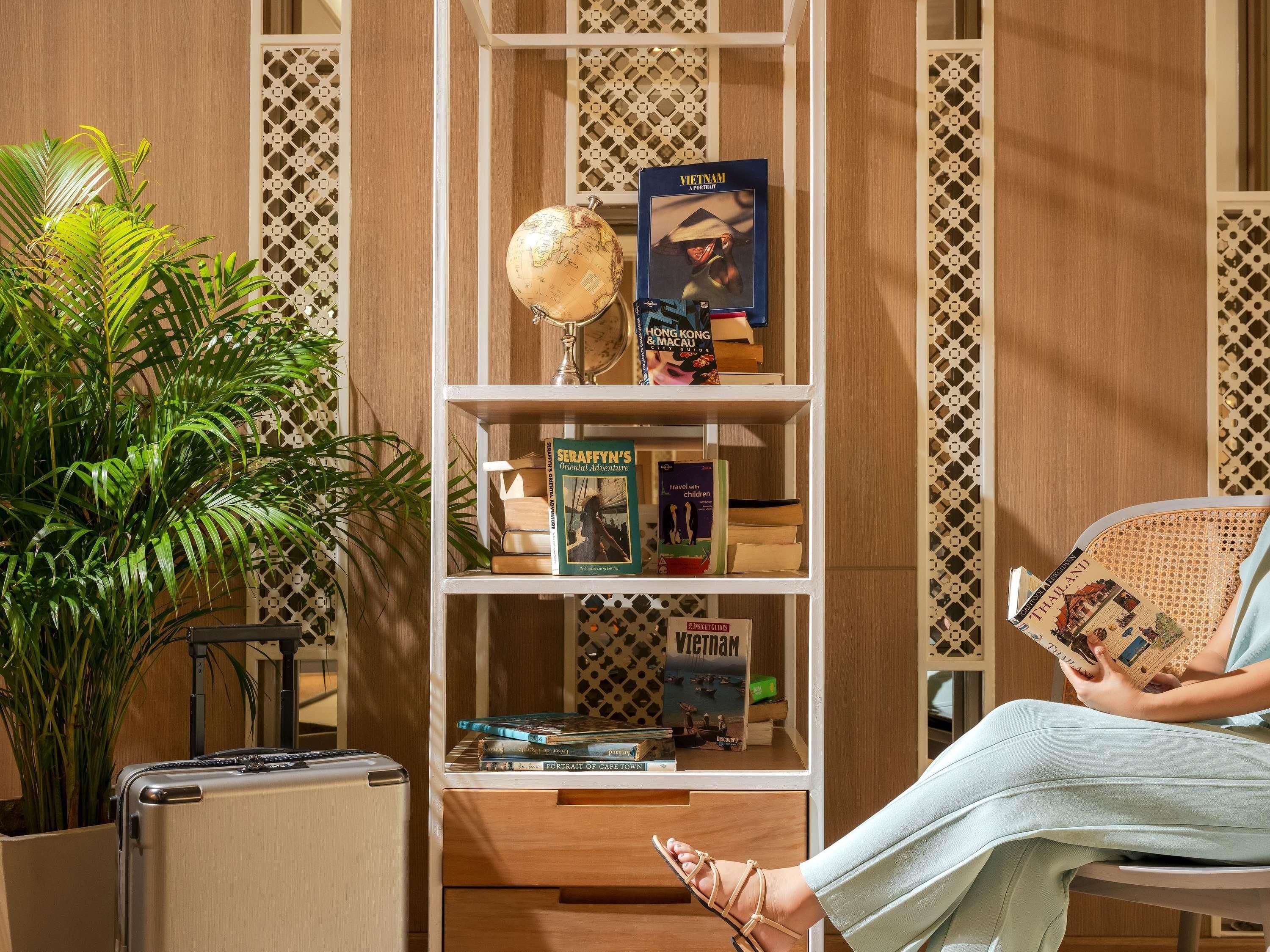 Una habitación con una estantería que contiene libros de viajes, un globo terráqueo y una maleta.