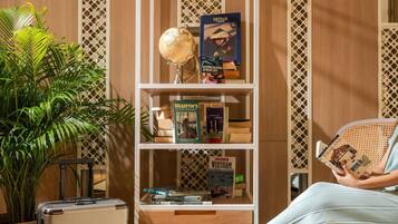Una habitación con una estantería que contiene libros de viajes, un globo terráqueo y una maleta.