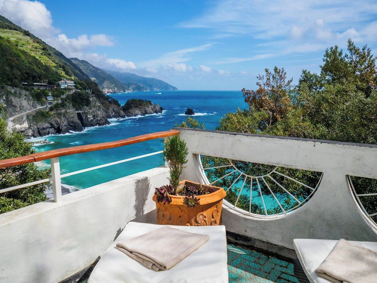 A poolside area with a view of the ocean and a mountainous landscape.