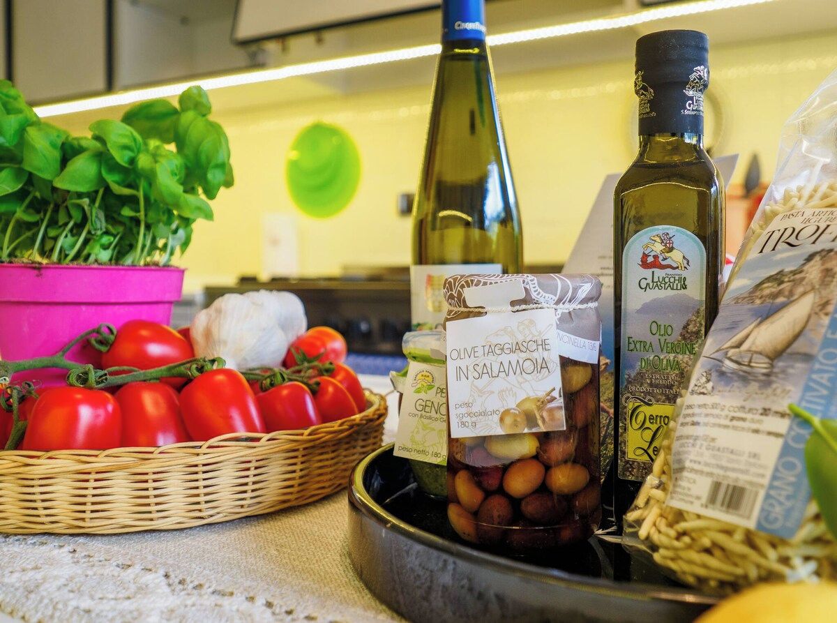 Een aanrecht met verse producten, zoals tomaten en basilicum, en flessen olijfolie.
