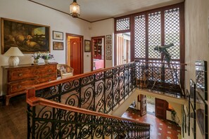 Un escalier orné de rampes en métal, un banc en bois, une lampe et un tableau accroché au mur.