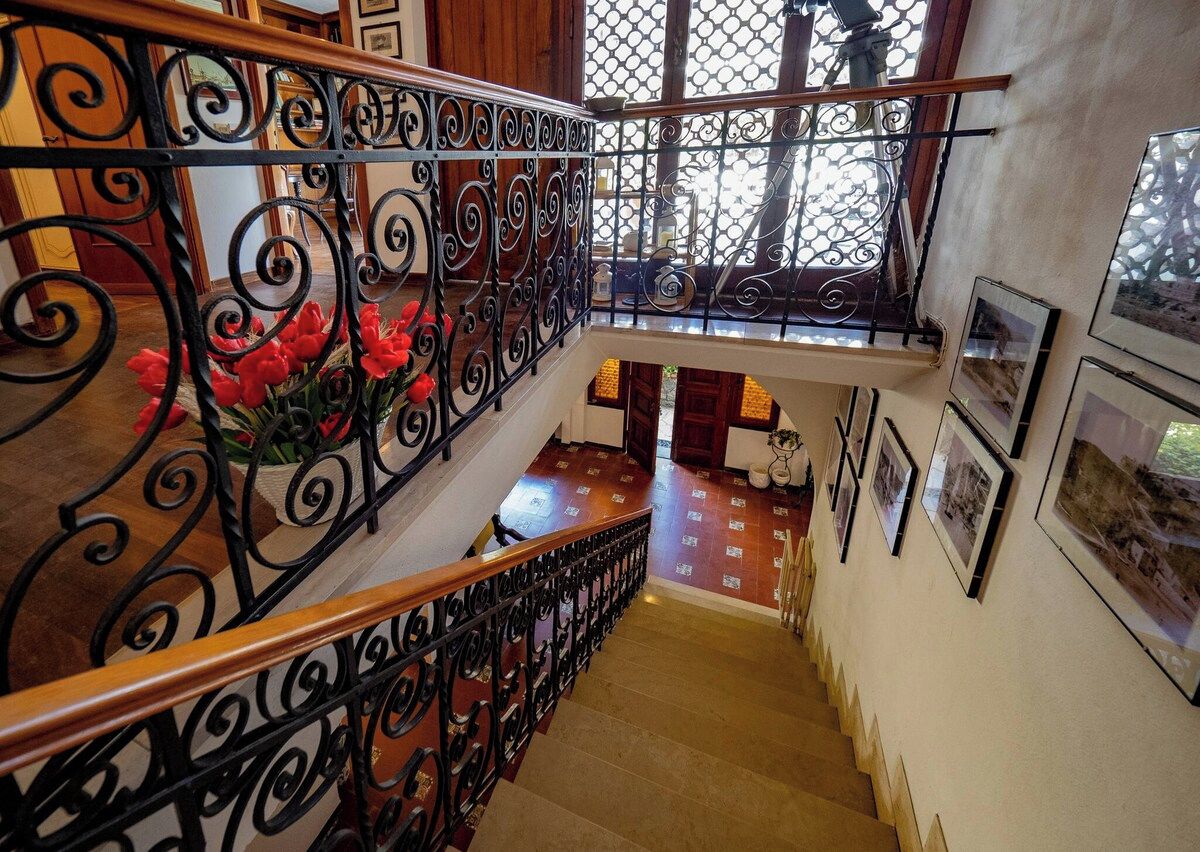 A staircase with ornate black metal railings and a wooden handrail.