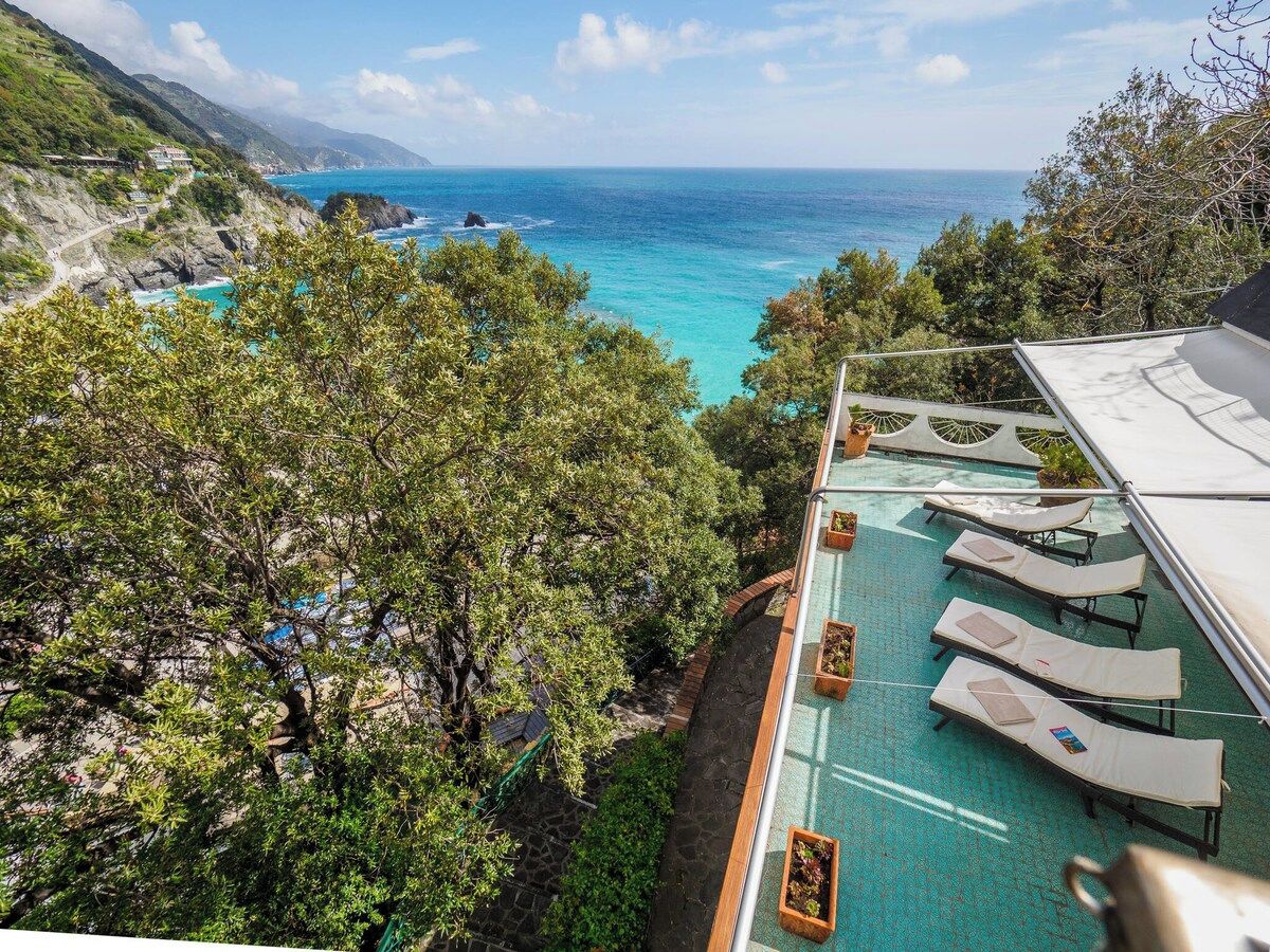 Un espace piscine avec des chaises longues et une vue sur l’océan.