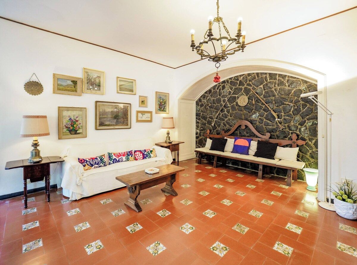 A room with a white sofa, a wooden bench, a chandelier, and a stone wall.