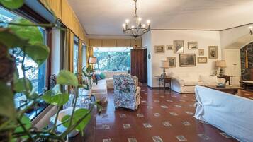 A spacious living room with a patterned floor, a chandelier, and a view through the window.