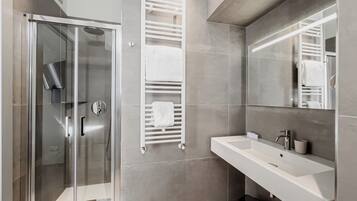 Un bagno moderno con cabina doccia in vetro, lavandino bianco e uno specchio grande.