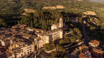 An aerial view of a historic town with a prominent church featuring a bell tower, surrounded by traditional buildings and lush greenery.