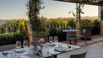 Une terrasse avec des tables dressées pour le dîner, offrant une vue sur un paysage montagneux.
