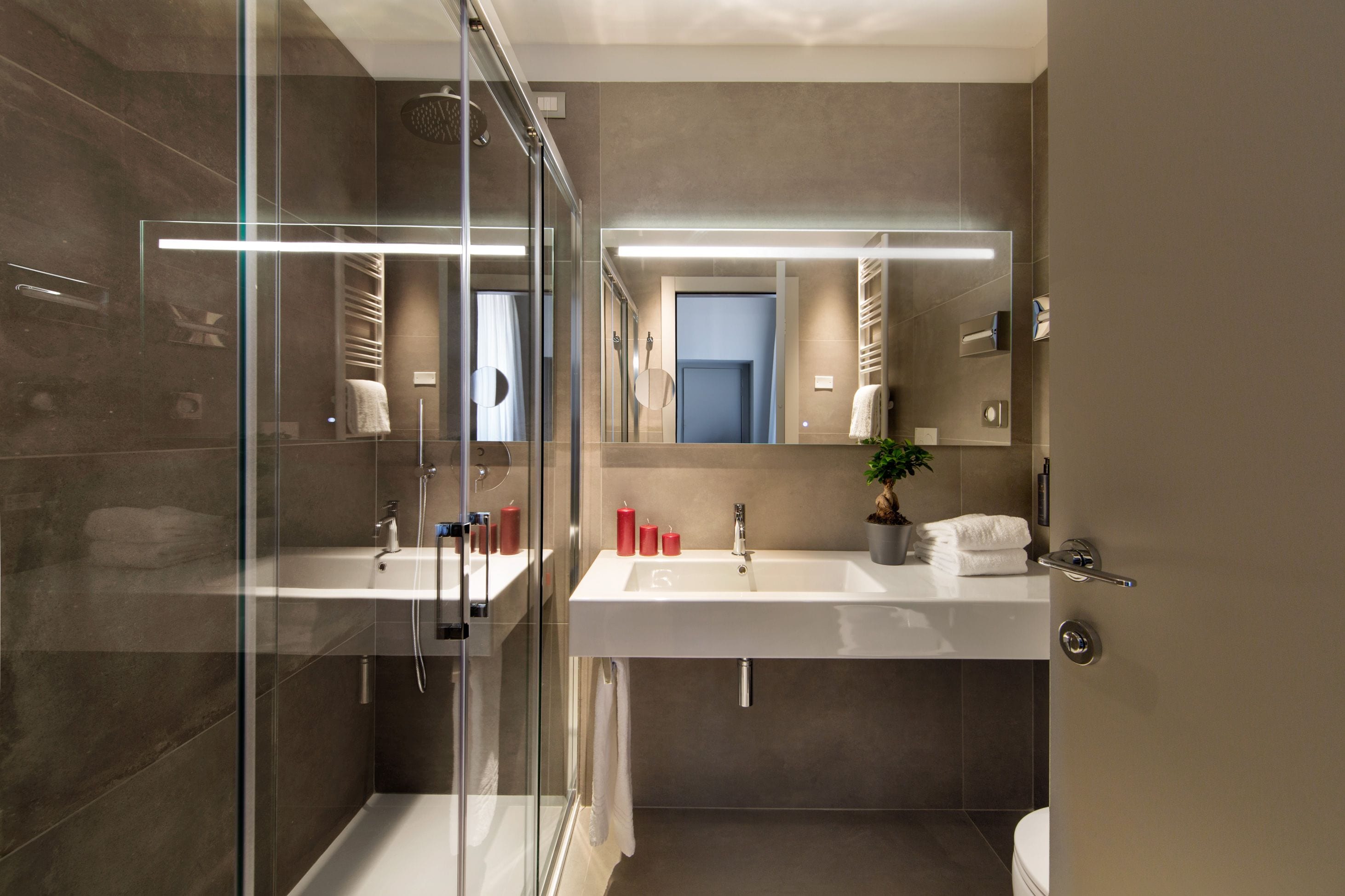 A modern bathroom with a glass shower enclosure, two sinks, and a large mirror.