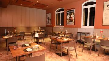 Un restaurant doté de nombreuses tables et chaises, disposées dans un espace vaste et aéré, avec de hauts plafonds et de grandes fenêtres.