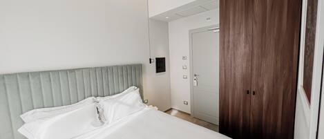 Una habitación de hotel con una cama, un armario de madera y una puerta.