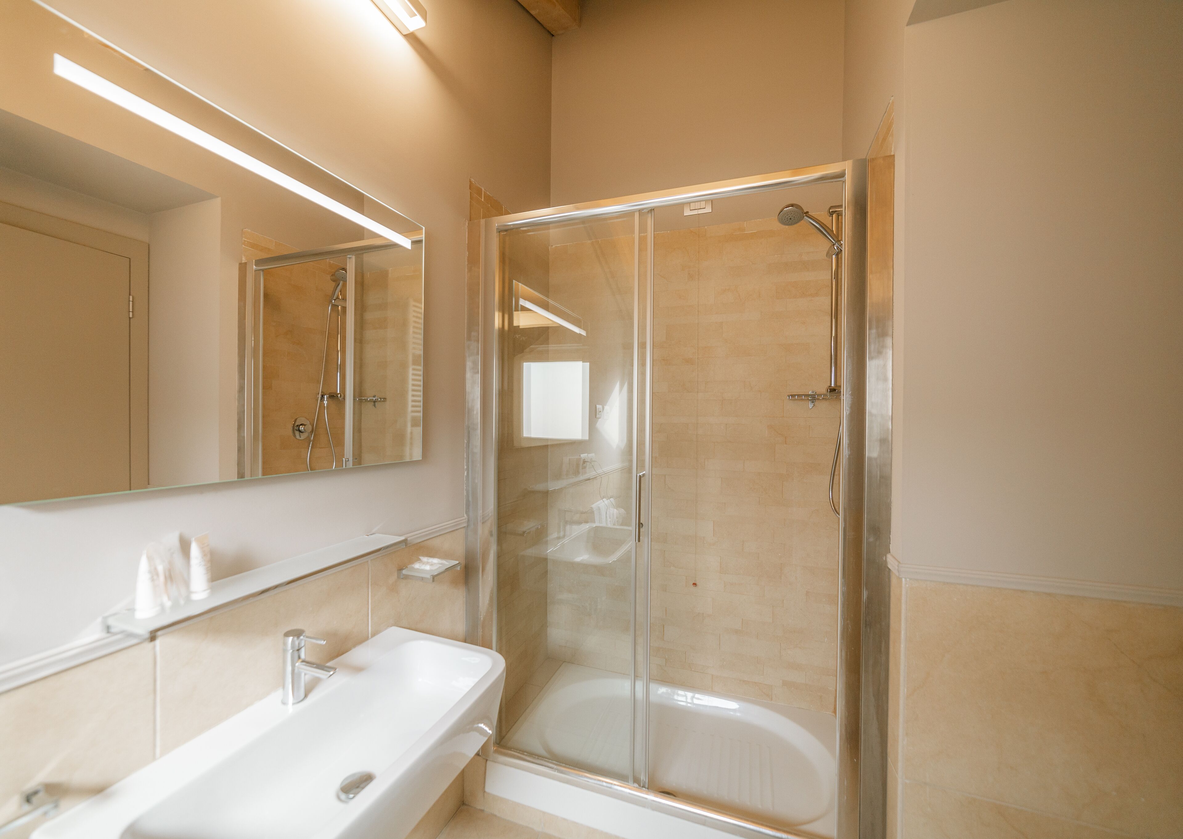 Une salle de bain moderne avec une douche à parois de verre, un lavabo blanc et un grand miroir.