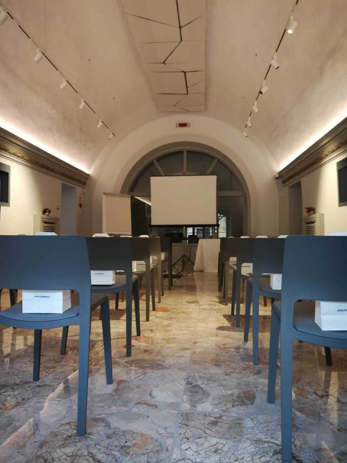 Une salle de conférence avec des rangées de chaises et un grand écran à l’avant.