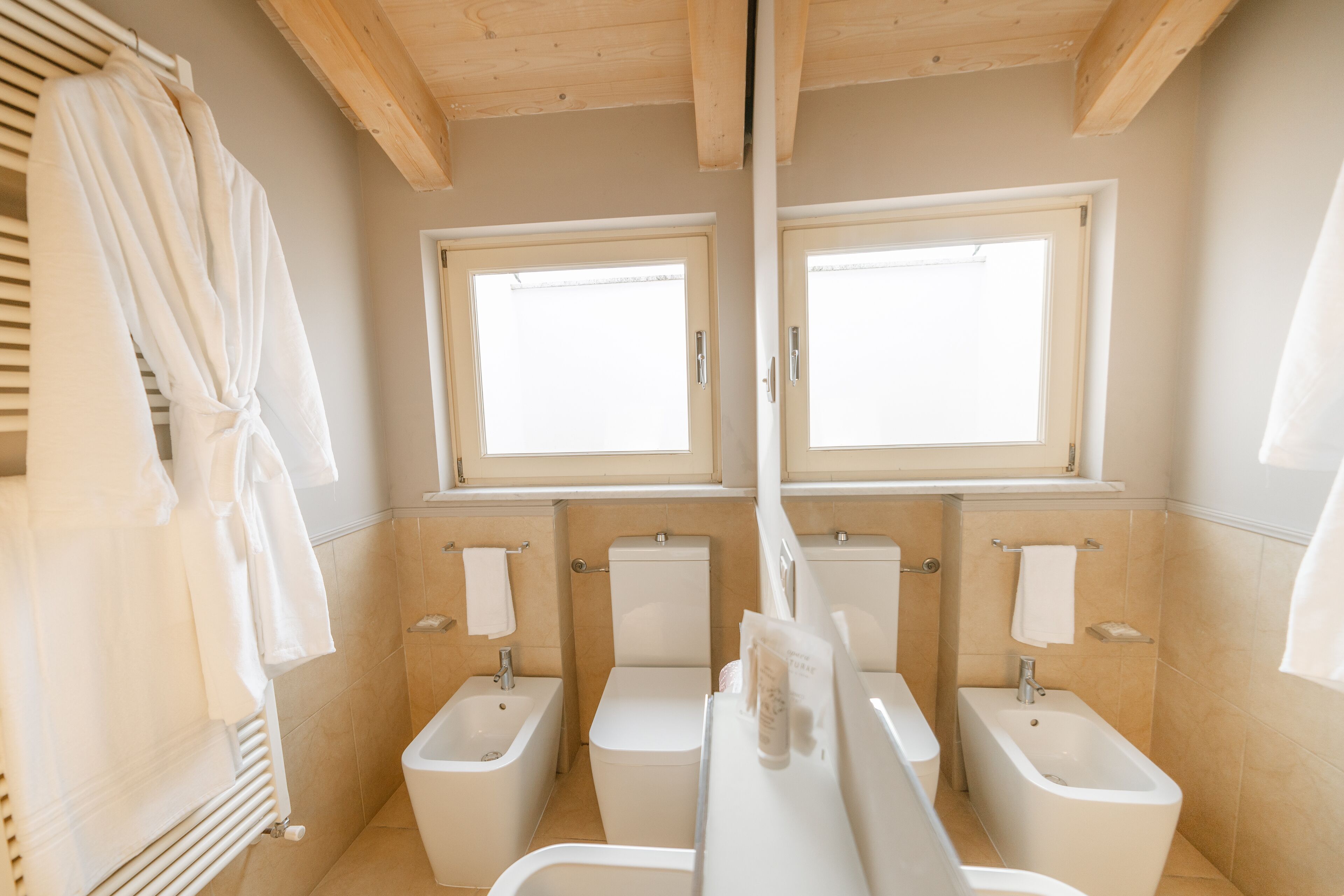 A modern bathroom with two toilets, a bidet, and a bathtub.