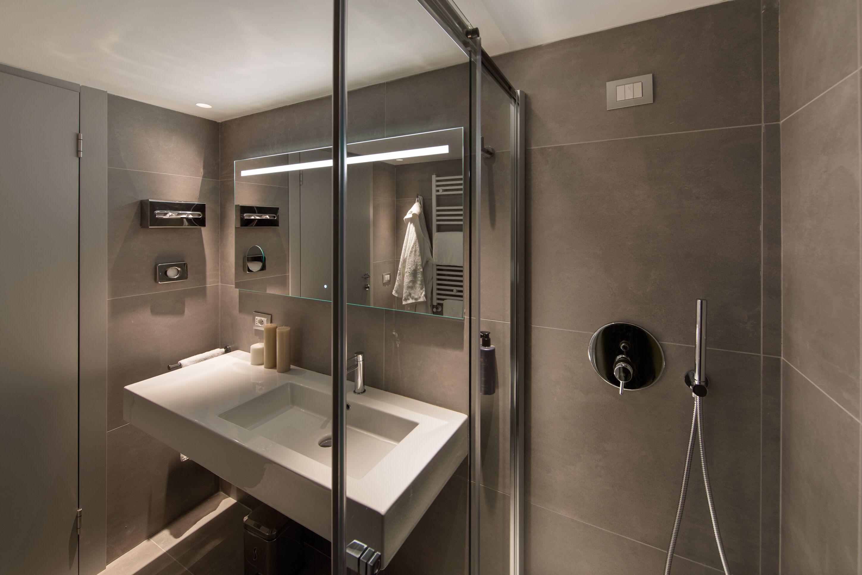 Une salle de bain moderne avec une douche à parois de verre, un grand lavabo et un miroir.