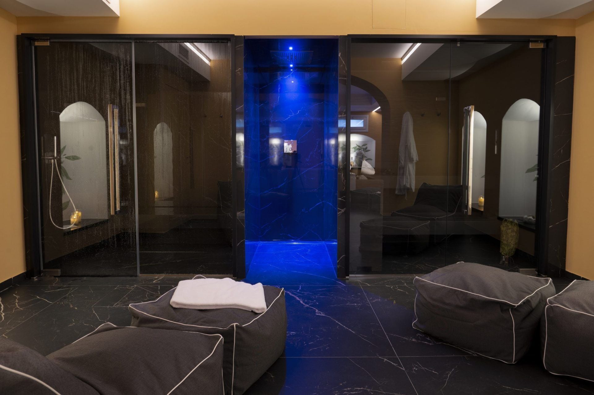 Un espace de détente moderne avec une paroi en verre, une fontaine illuminée de couleur bleue et des coins salon confortables.