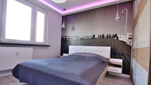 Quarto com uma cama grande, vista para um cais e iluminação moderna.