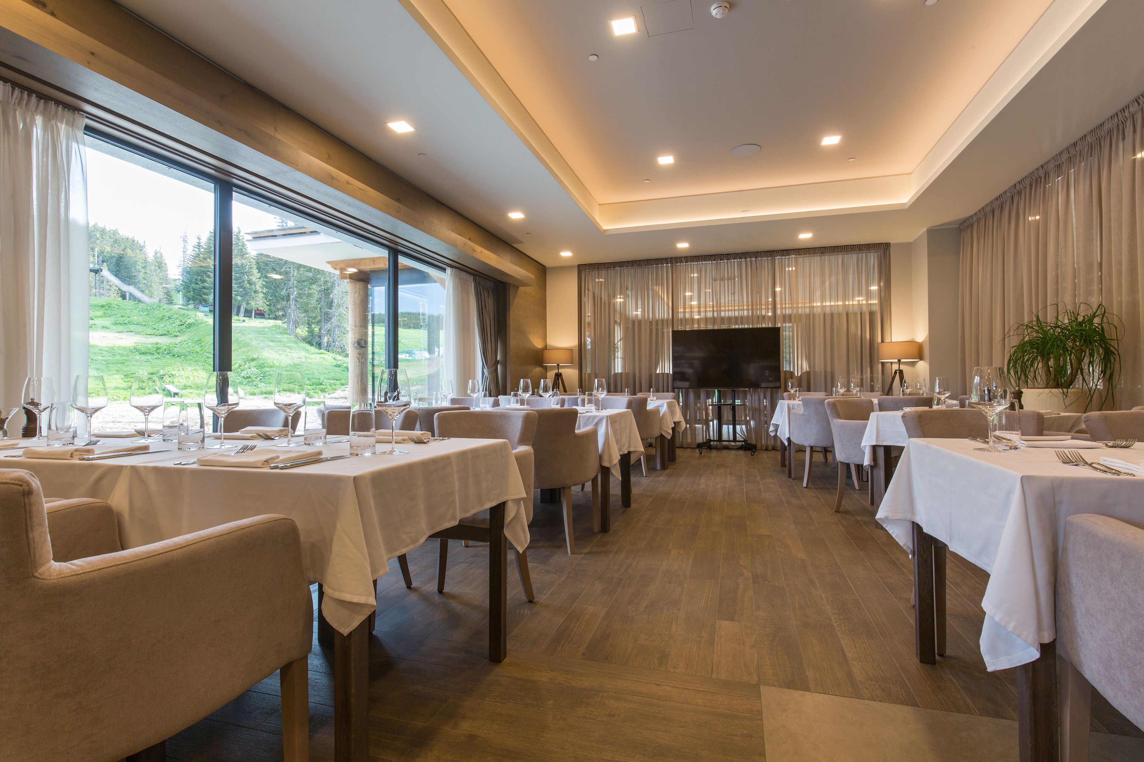 Un restaurante con varias mesas, sillas y una gran pantalla de televisión.