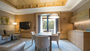 A modern living room with a dining area, wooden ceiling, and a large window with curtains.