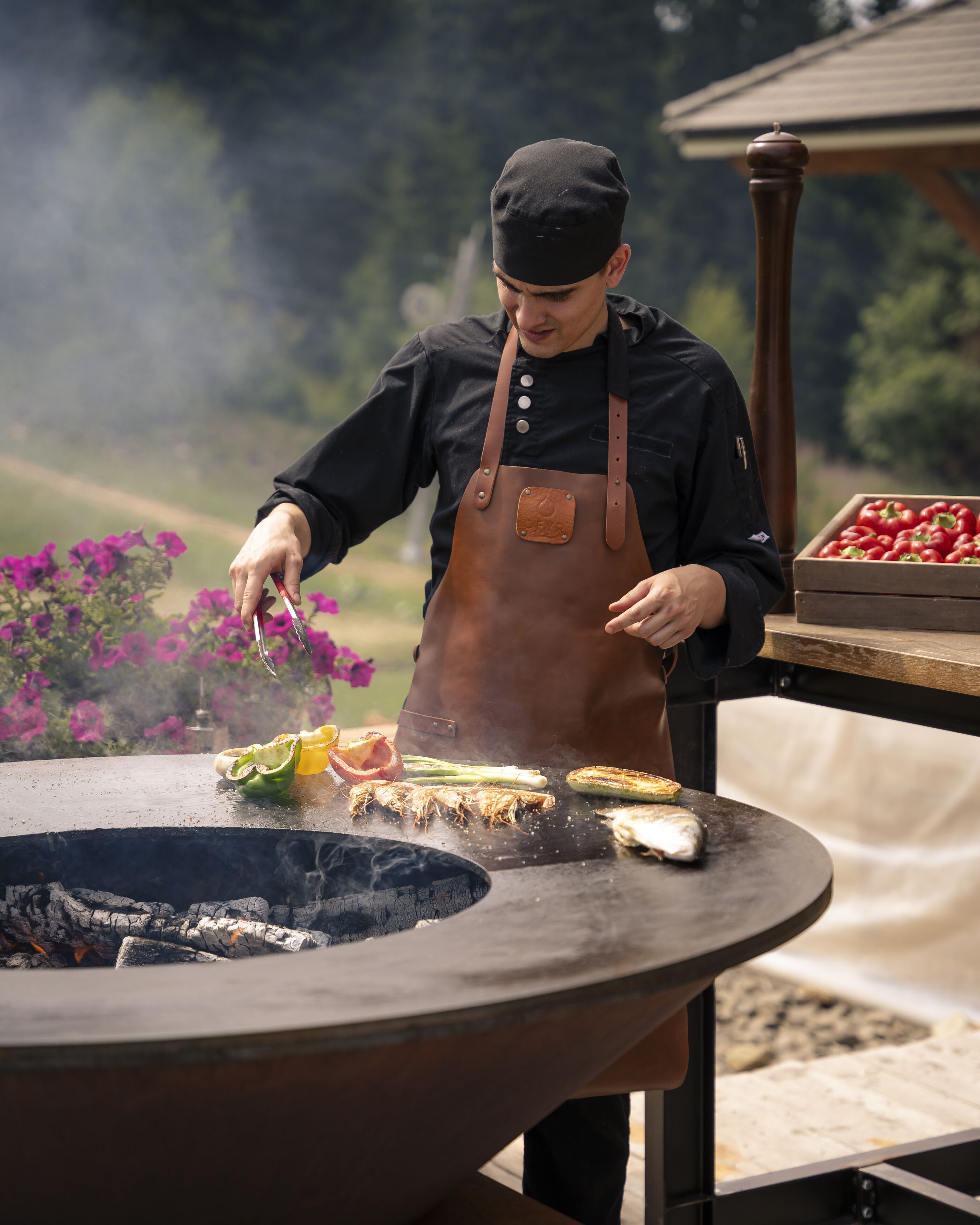 A chef grilling vegetables outdoors.
