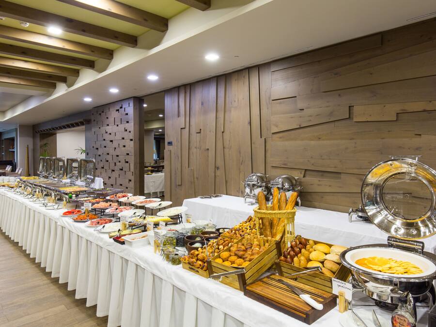 A buffet setup with various food items and a bread basket.