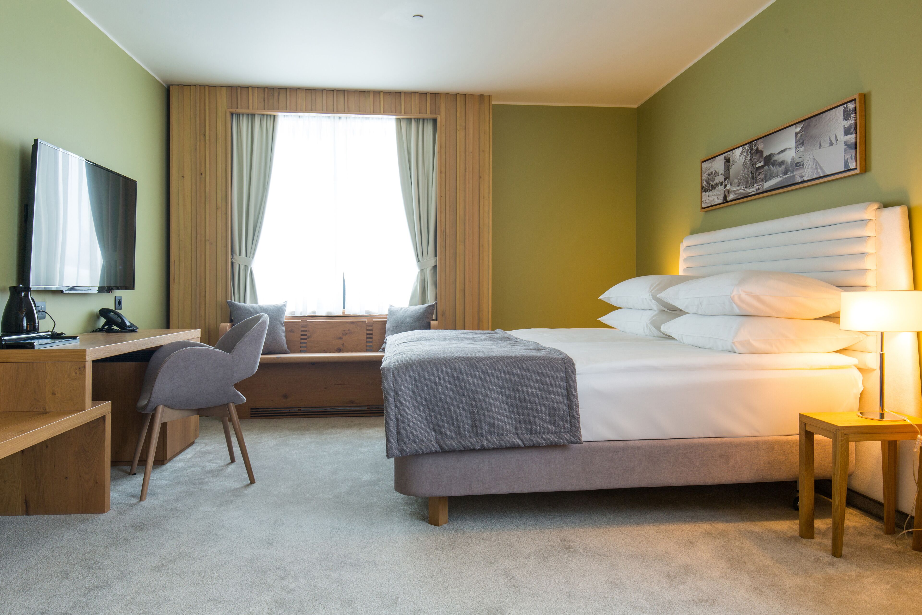 Ein Hotelzimmer mit Bett, Schreibtisch, Stuhl und Fernseher.