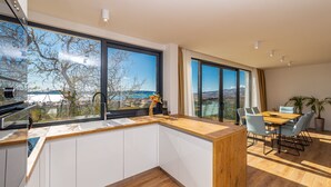 Eine moderne Küche mit großen Fenstern, einer Holzausziehtafel und einem Essbereich mit Tisch und Stühlen.