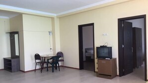Ein Wohnzimmer mit Esstisch, Stühlen, einem Fernseher auf einem Schrank und einem Kleiderschrank.