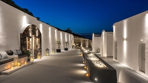 A modern hotel corridor with white walls, stone archways, and a long bench.